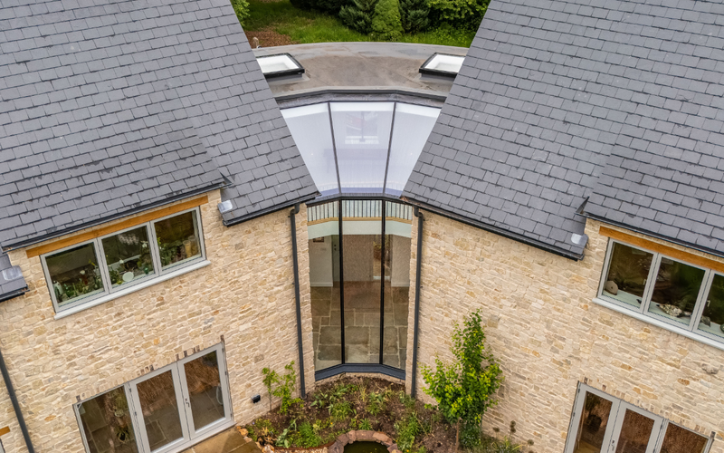 Glass roof design connecting two pitched roof sections in a residential property